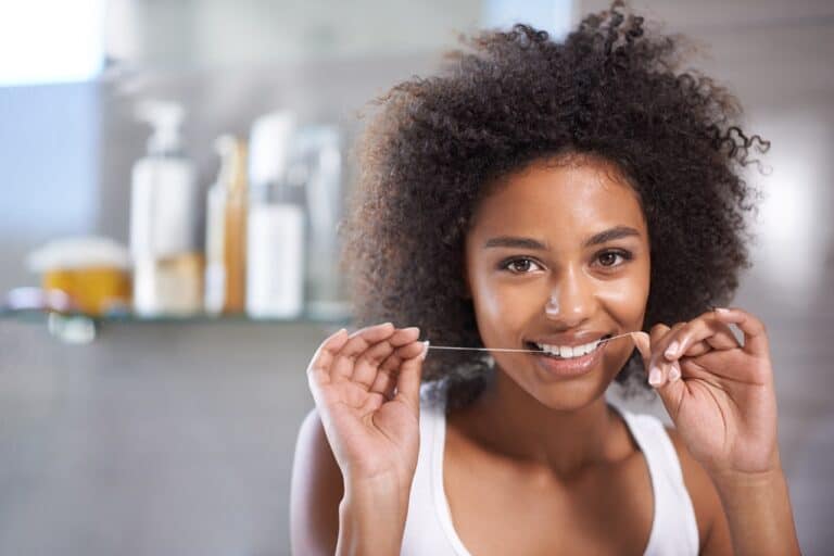 young black woman flossing her veneers and teeth
